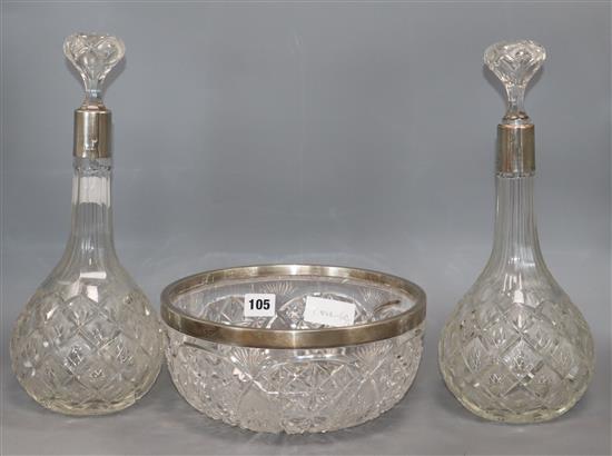 A pair of silver collared cut glass decanters and a similar bowl